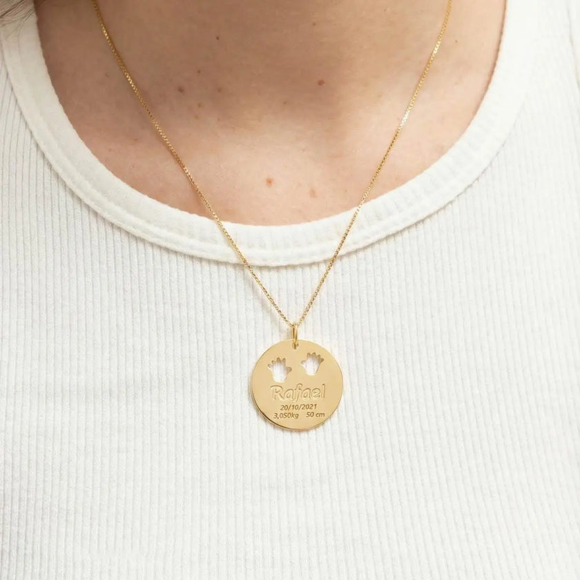 Pingente nascimento com mãozinha personalizado com nome em banho ouro 18k usado no colo, em composição delicada e afetiva.